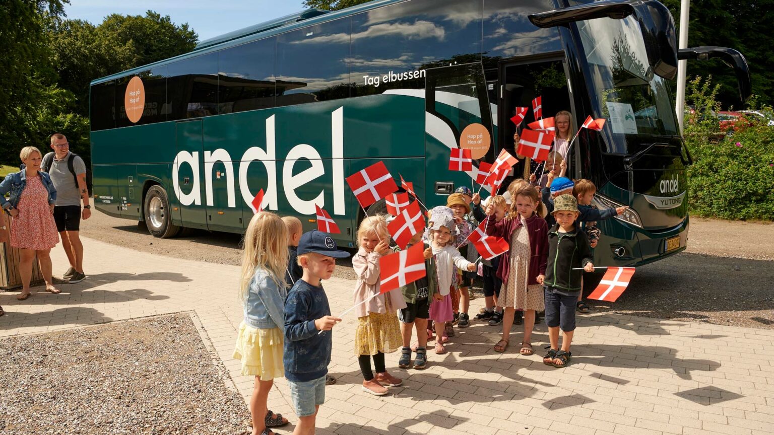 Børn med flag på vej ud af elbus fra Andel