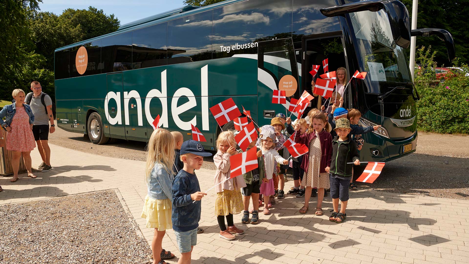 Børn med flag på vej ud af elbus fra Andel